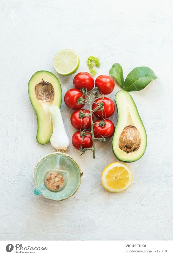 Frische Salatzutaten. Hälften von Avocado, Tomaten, Zitrone und Olivenöl auf weißem Hintergrund. Ansicht von oben. Vegetarisches Essen. Gesunde Ernährung frisch