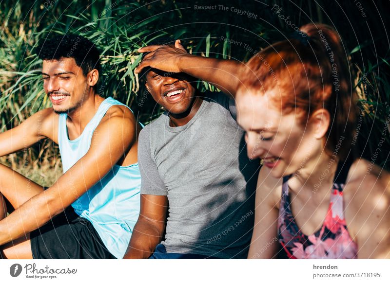 drei Freunde, die auf einer Bank sitzen, nachdem sie im Freien trainiert haben Freundschaft Sitzen Menschen trainiert. Sport Gesunder Lebensstil