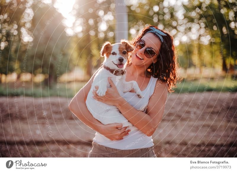 junge glückliche Frau in einem Auto, die ihren süßen Hund kuschelt. Reisekonzept Sonnenuntergang im Freien Liebe Zusammensein Park jack russell Lifestyle