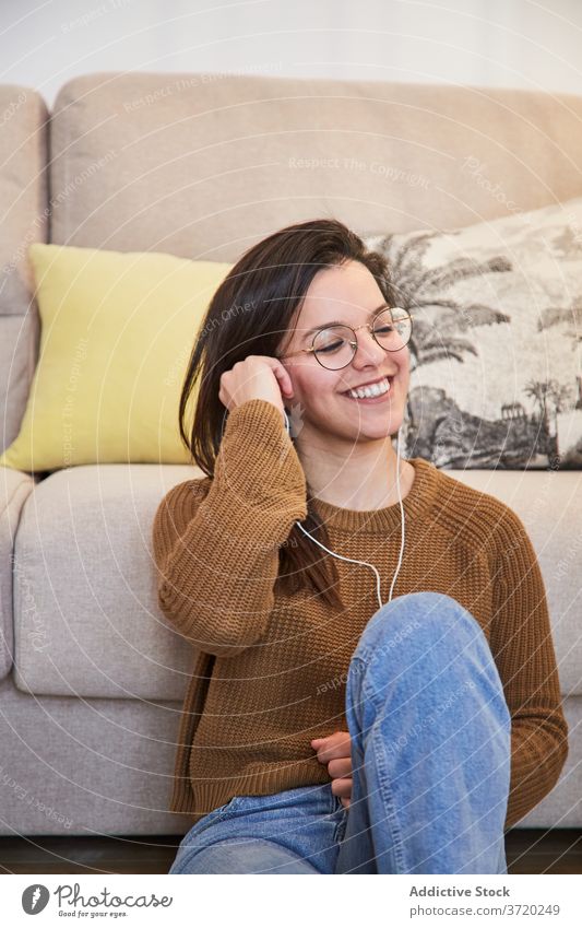 Zufriedene Frau, die mit ihrem Smartphone Musik hört zuhören tausendjährig genießen Talkrunde benutzend soziale Netzwerke Kopfhörer jung Mobile Telefon