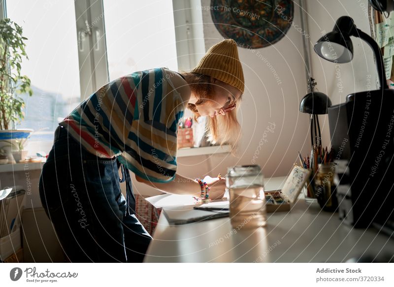 Fröhliche Frau malt in der Werkstatt Künstler Farbe Wasserfarbe kreieren Handwerkerin heiter Fähigkeit Anstreicher Kunstwerk Hobby Inspiration trendy Atelier