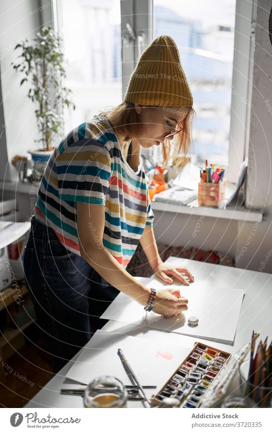 Fröhliche Frau malt in der Werkstatt Künstler Farbe Wasserfarbe kreieren Handwerkerin heiter Fähigkeit Anstreicher Kunstwerk Hobby Inspiration trendy Atelier