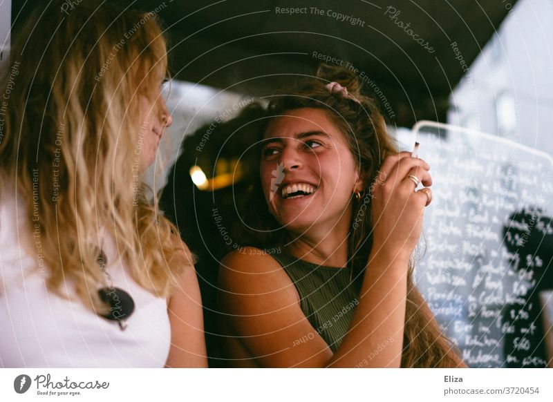 Zwei Freundinnen sitzen draußen im Café und lachen zusammen Bar rauchen Spaß haben Sommer Fröhlichkeit zwei unterhalten ausgehen Lifestyle Freundschaft