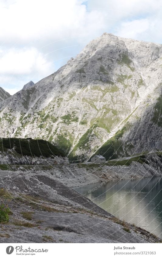 Lünersee in den Bergen mit kleinem Steinhaus auf dem Stausee Österreich wandern Lichtspiel Schatten Einsam herrliche Aussicht Seeufer Felsen Wege & Pfade Sommer