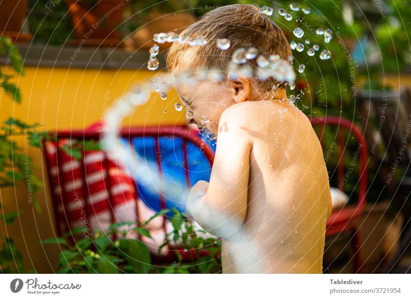 Junge wird auf der Terrasse mit Wasser bespritzt und dreht sich weg platschen spritzen Kind nackt Haut Garten Balkon Planschbecken Garten-Schleife Tropfen