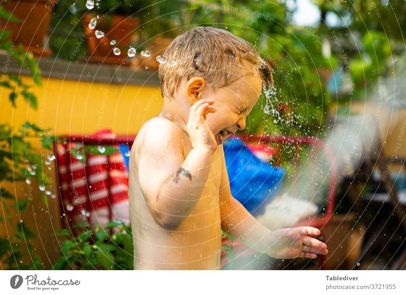 Junge wird auf der Terrasse mit Wasser bespritzt und dreht sich weg platschen spritzen Kind nackt Haut Garten Balkon Planschbecken Garten-Schleife Tropfen