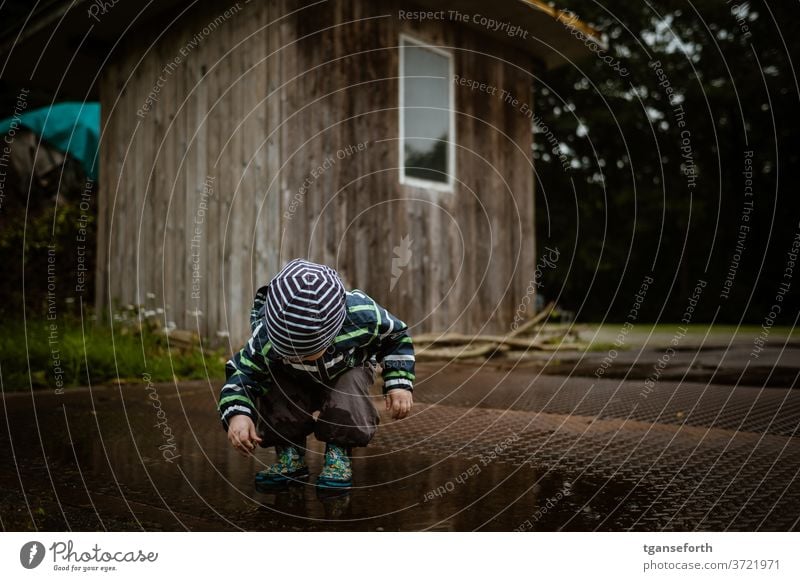 Junge spielt in Pfütze Kind Kindheit Spielen spielende Kinder Außenaufnahme Freude Menschen entdecken beobachten 1-3 Jahre Kindererziehung Kleinkind