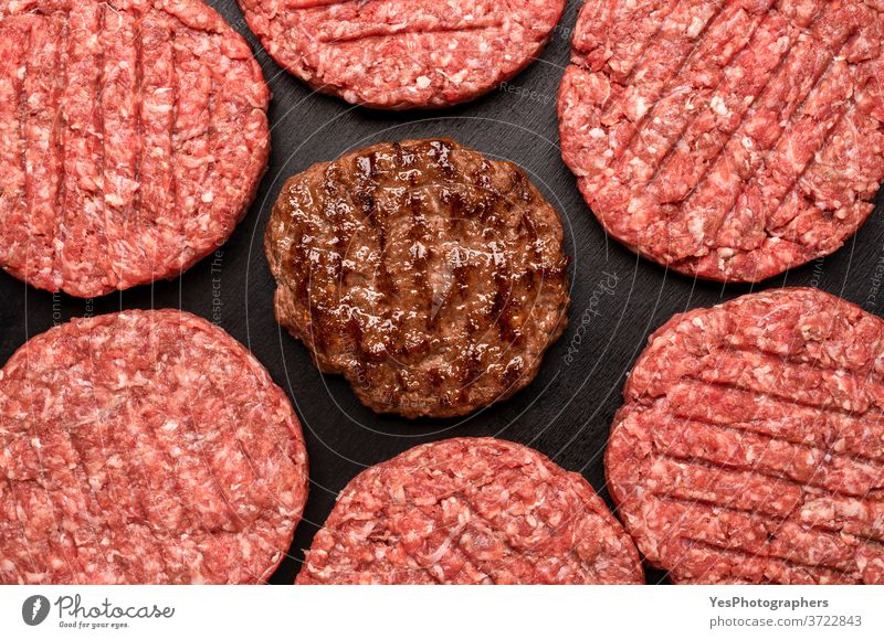 Hamburger Frikadellen von oben auf schwarzem Tisch. Gegrillte und rohe Rinderpasteten obere Ansicht Hintergrund Barbecue grillen Rindfleisch Burger Metzger