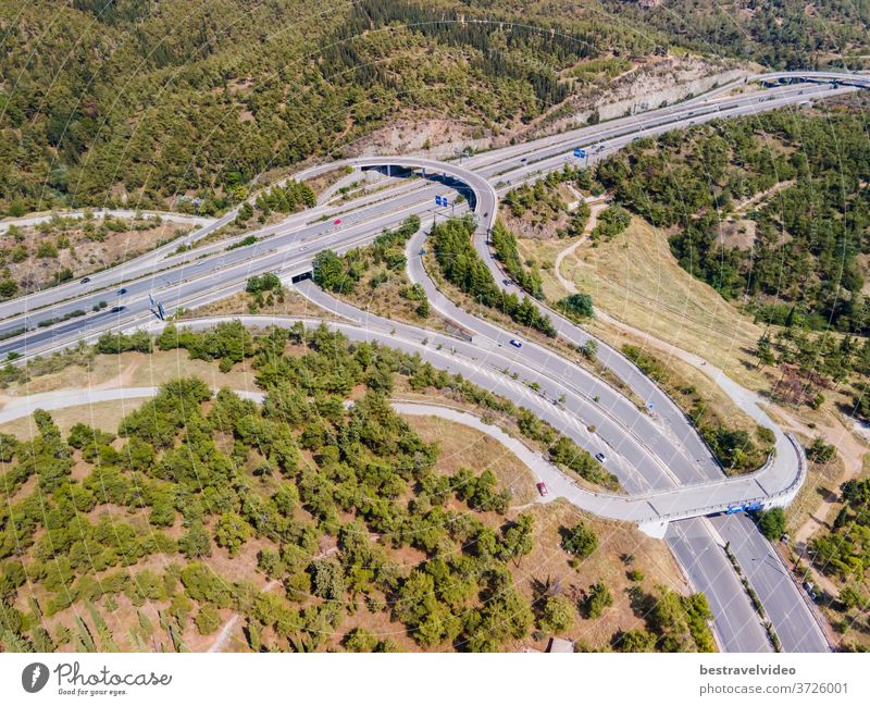 Thessaloniki, Griechenland: Drohnenlandschaft des Kreuzungsverkehrs auf der inneren Ringstraße Periferiaki. Tagesspitzenpanorama eines europäischen Mehrebenen-Stapelautobahnkreuzes mit vorbeifahrenden Autos durch Wald.