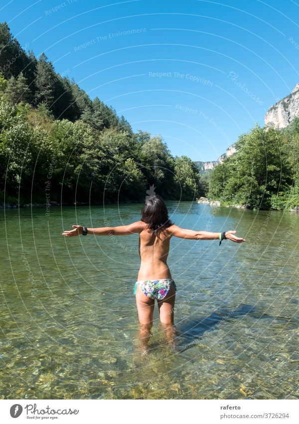 Rückansicht einer Frau mit erhobenen Armen, die beim Baden in den Fluss steht 1 Wasser nass jung Erwachsener Arme hochgezogen Behaarung schön Schönheit Mädchen