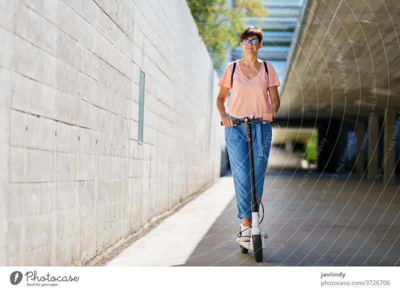 Frau fährt auf einem Elektroroller durch die Stadt Tretroller elektrisch Mädchen Öko Transport urban Lifestyle modern Freizeit Großstadt Mitfahrgelegenheit