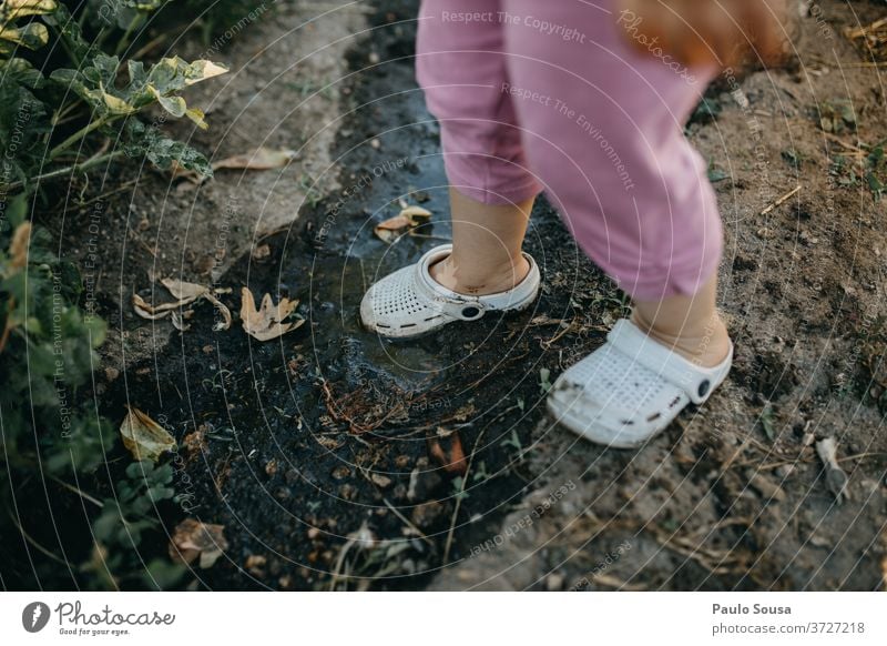 Kind mit Crocs auf dem Schlamm Gummi Krokodile Schuhe schlammig Komfortabel dreckig Farbfoto Natur Erde Tag Außenaufnahme braun Mensch Gummistiefel grün Pfütze