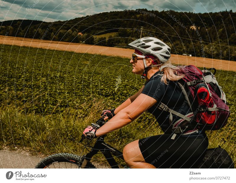 Junge Frau auf dem Mountainbike bei einer Radtour mountainbike radtour junge frau mädchen helm sportlich outdoor sonnebrille trikot rucksack lächeln spaß