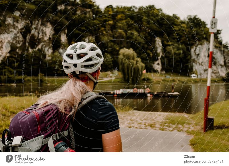 Junge Radfahrerin wartet auf Wassertaxi radfahren mtb junge frau blond hübsch helm Rucksacktourismus rucksack radtour bayern kehlheim wasser boot