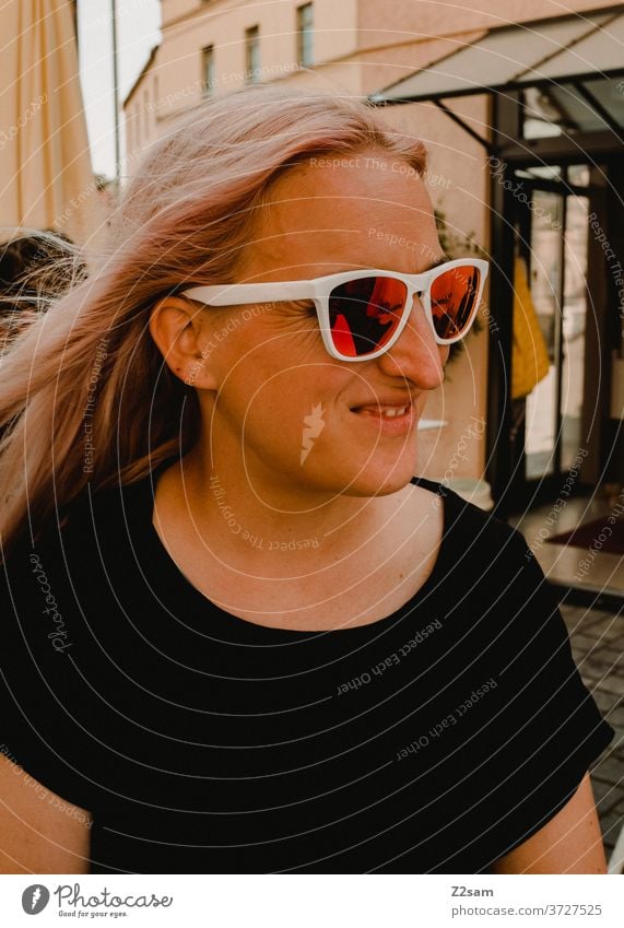 Junge Frau mit Sonnenbrille junge frau blond hübsch schön sonnebrille lachen lächeln glücklich zufrieden t-shirt schwarz innenstadt attraktiv Fröhlichkeit