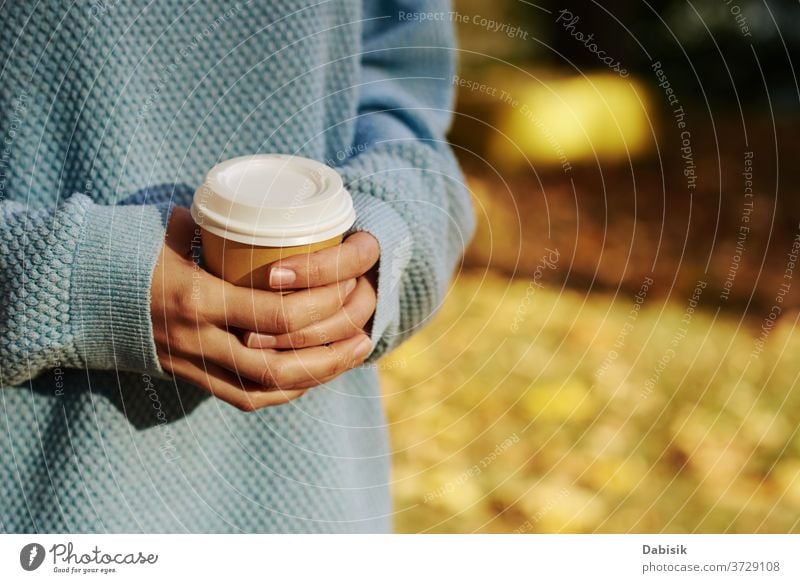 Frau hält Tasse Kaffee zum Mitnehmen im Herbstpark im Freien weg Tee trinken Einwegartikel Papier Hand gehen Sie heiß Morgen Latte Imbissbude Halt Beteiligung