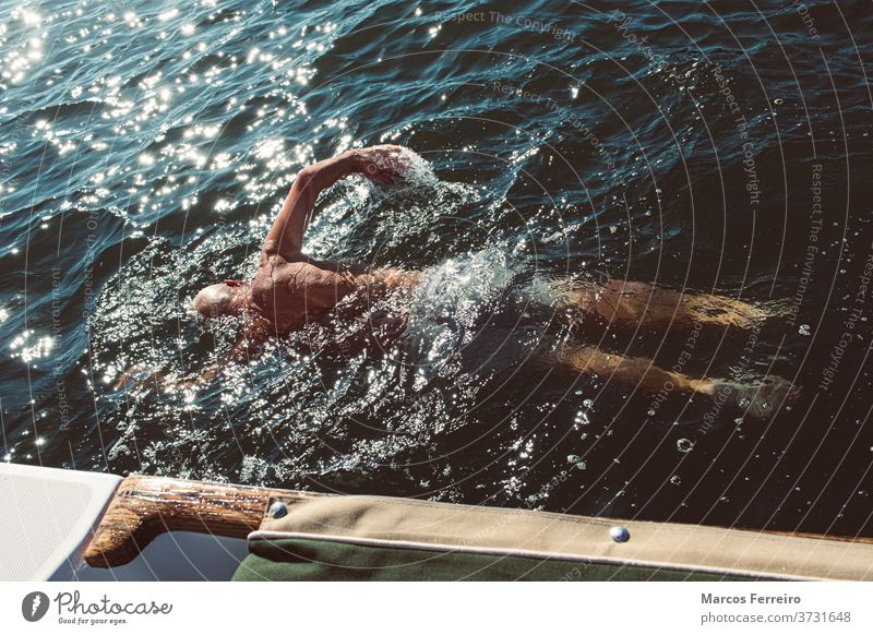 älterer Mann, der neben seinem Boot im Meer schwimmt Erholung Windstille im Freien Europäer Segeln Aktivität Übung Jacht Schwimmsport Tourismus schön Menschen