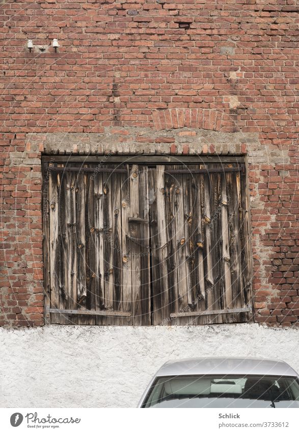 Uraltes Garagentor akzeptiert keine Autos mehr Holz Autodach Holztor uralt verwittert unzugänglich Backsteinwand Fassade frontal Alt und Neu Gegensatz Parken