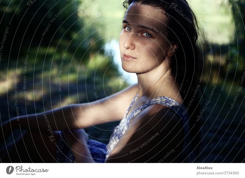 Nahes Portrait einer jungen Frau an einem Seeufer in der Natur mit Licht und Schatten durch Bäume schönes Wetter Stimmung selbstbewußt Kleid nasse haare