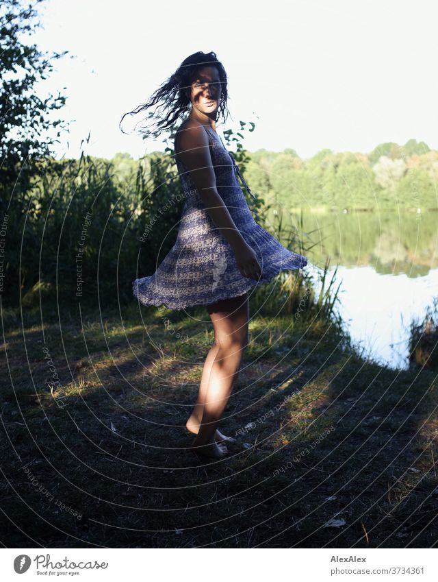 Nahes Portrait einer jungen Frau an einem Seeufer in der Natur mit Licht und Schatten durch Bäume schönes Wetter Stimmung selbstbewußt Kleid nasse haare