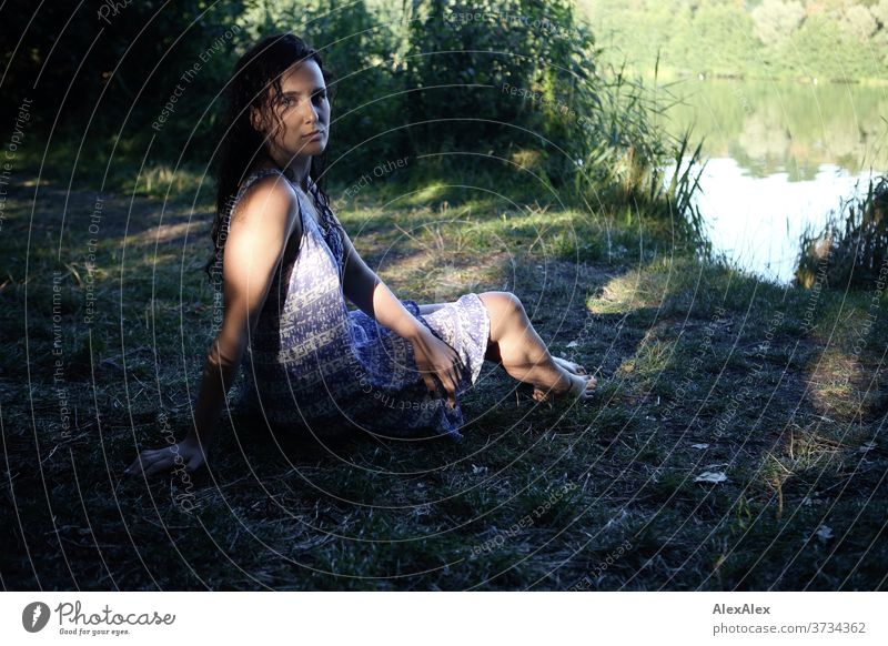 Nahes Portrait einer jungen Frau an einem Seeufer in der Natur mit Licht und Schatten durch Bäume schönes Wetter Stimmung selbstbewußt Kleid nasse haare