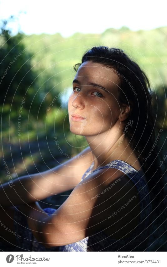 Nahes Portrait einer jungen Frau an einem Seeufer in der Natur mit Licht und Schatten durch Bäume schönes Wetter Stimmung selbstbewußt Kleid nasse haare