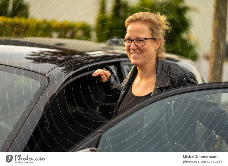 Junge Frau steigt in ein Auto Autofahren Verkehr Außenaufnahme Farbfoto Autotür PKW PKWs Verkehrsmittel Fahrzeug Dame Lederjacke Tag Frauengesicht Frauenbrust