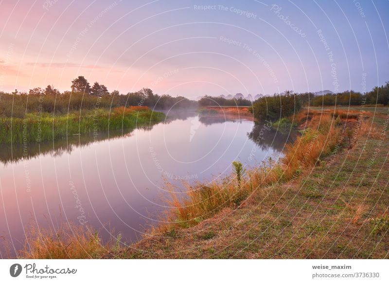 Nebliger Sonnenaufgang im Herbst am Fluss. Farbenfrohe Morgendämmerung. Bewölkter Sonnenaufgang. Reflexion & Spiegelung Himmel im Freien Natur Landschaft reisen