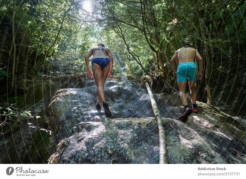 Reisendes Paar beim Klettern am Felsen im Sommer Aufstieg Klippe reisen Abenteuer felsig Wald Berghang Badebekleidung Feiertag Aktivität Freiheit Natur Urlaub