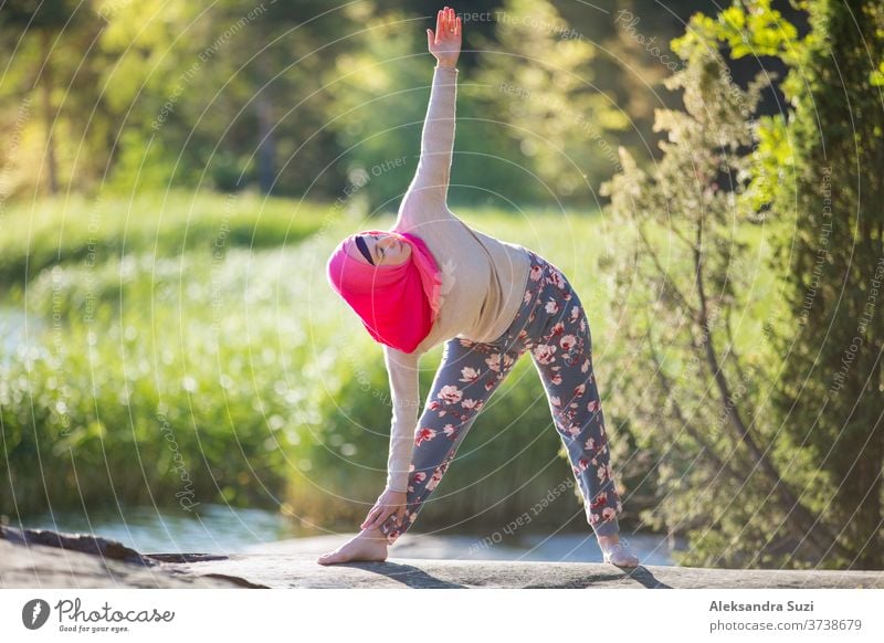 Attraktive Frau beim Hijab-Training im Park, meditierend. Sie macht Yoga-Übungen an der frischen Luft und genießt den frühen Morgen. Gesunder Lebensstil