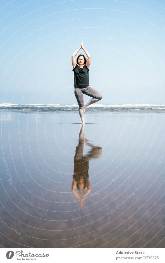 Junge Frau in balancierenden Yoga-Asana stehend am Strand MEER üben Pose Baum vrksasana Gleichgewicht Windstille Meeresufer Harmonie Augen geschlossen Wellness