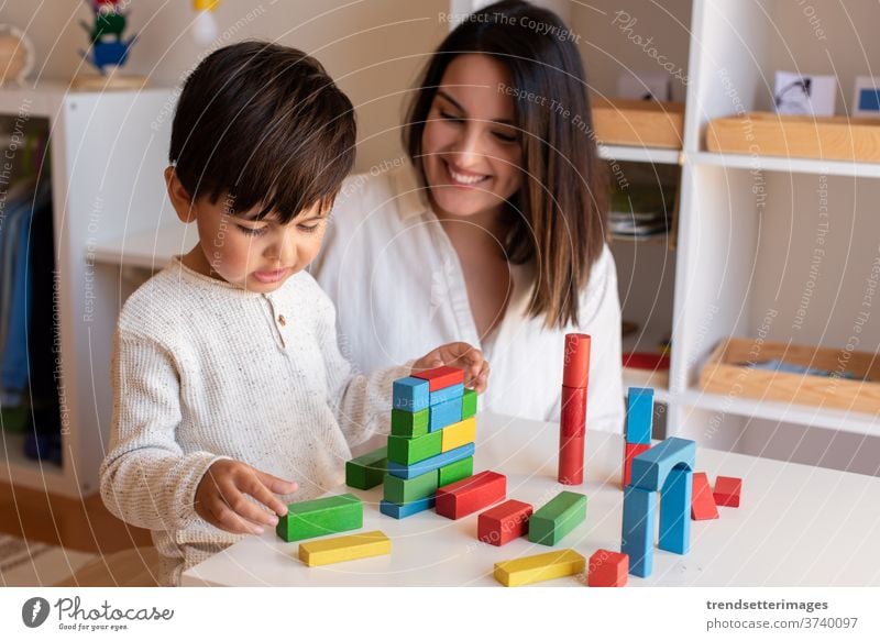 Vorschulkind, das mit Holzklötzen spielt, und Hilfe eines Lehrer-Pädagogen. Hausunterricht. Lernende Gemeinschaft. Montessori-Schule Blöcke Holzspielzeug Spiel