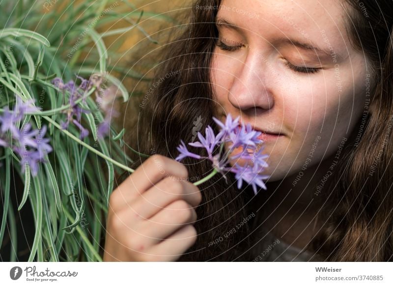 Junges Mädchen schnuppert genüsslich an der Knoblauchblume junge Frau riechen schnuppern Nase Duft Aroma Geruch intensiv Garten Blume natürlich Natur scharf