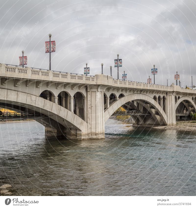 Brücke in Calgary über dem Bow River Fluss Kanada Alberta Bow river Fahnen Himmel Wolken Bögen Architektur Wasser Menschenleer Außenaufnahme Nordamerika Tag