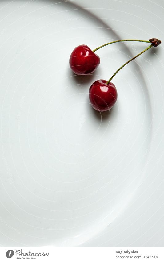 Zwei Kirschen auf einem weißen Teller Sauerkirschen Süßkirsche Frucht frisch süß reif Sommer Lebensmittel Minimalistisch Obst glänzend Ernte rot saftig