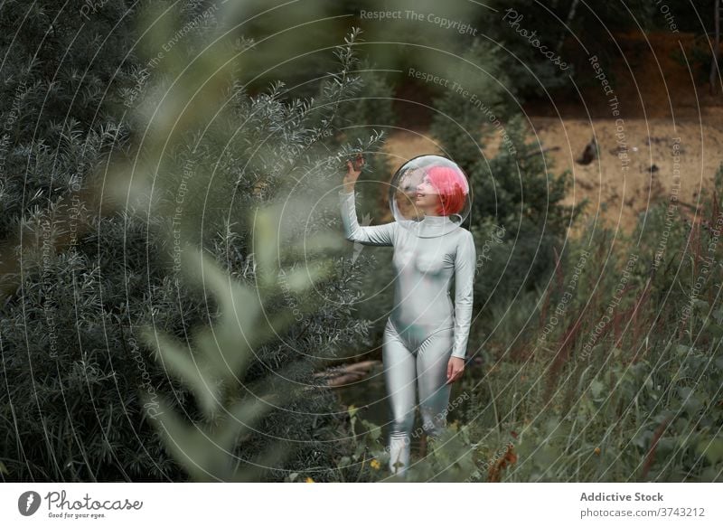 Frau im Raumanzug geht im Feld futuristisch Astronaut Schutzhelm Anzug Wald Natur positiv jung Kosmonaut Konzept Silber Lächeln beobachten selbstbewusst Glück