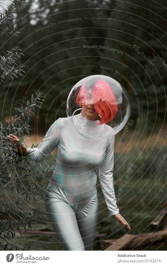 Frau im Raumanzug geht im Feld futuristisch Astronaut Schutzhelm Anzug Wald Natur positiv jung Kosmonaut Konzept Silber Lächeln beobachten selbstbewusst Glück