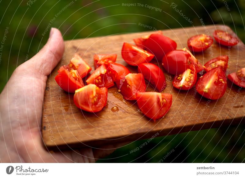 Geschnittene Tomate brett ernte ernährung essen kochen rezept schneidebrett selbstversrgung stück tomate zerschnitten küche schneidebrettchen hand lalten tragen