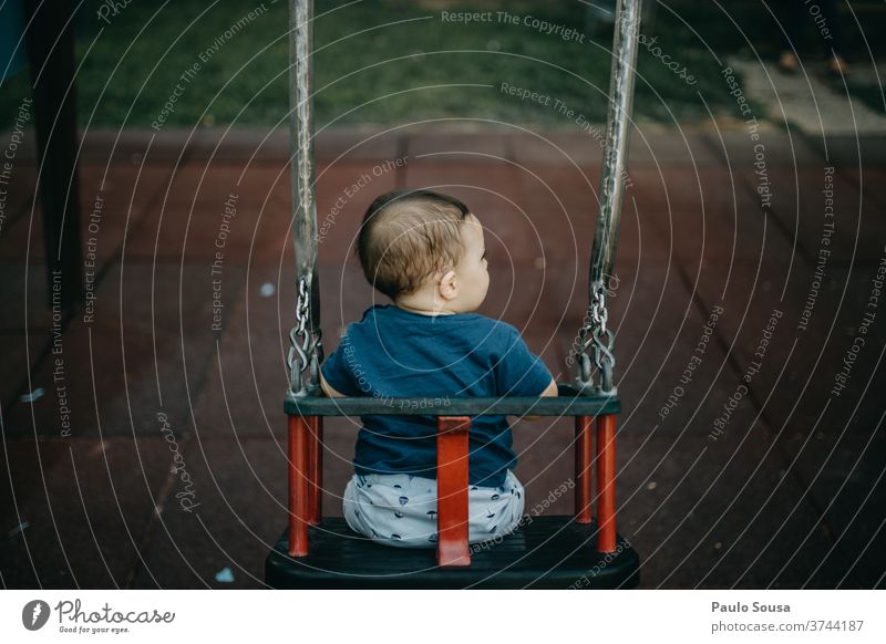 Rückansicht Kind spielt auf der Schaukel pendeln Spielplatz Kinderspiel Kindheit authentisch Textfreiraum unten Kleinkind Freizeit & Hobby Tag Farbfoto