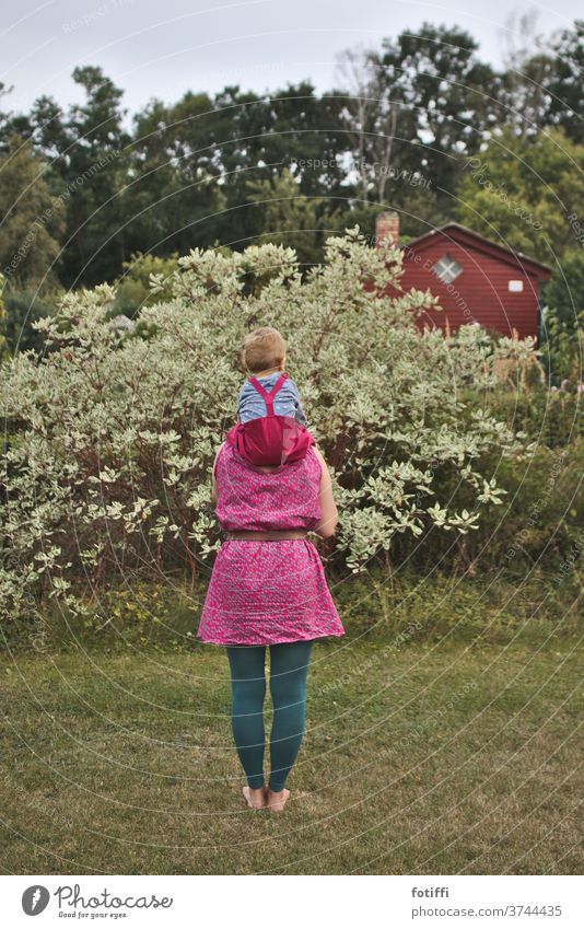 Huckepack mama huckepack pink Garten Kleingarten getragen getragen werden sitzen Kindheit Im Freien im Grünen Rücken Rückansicht Mama im Freien Zusammensein