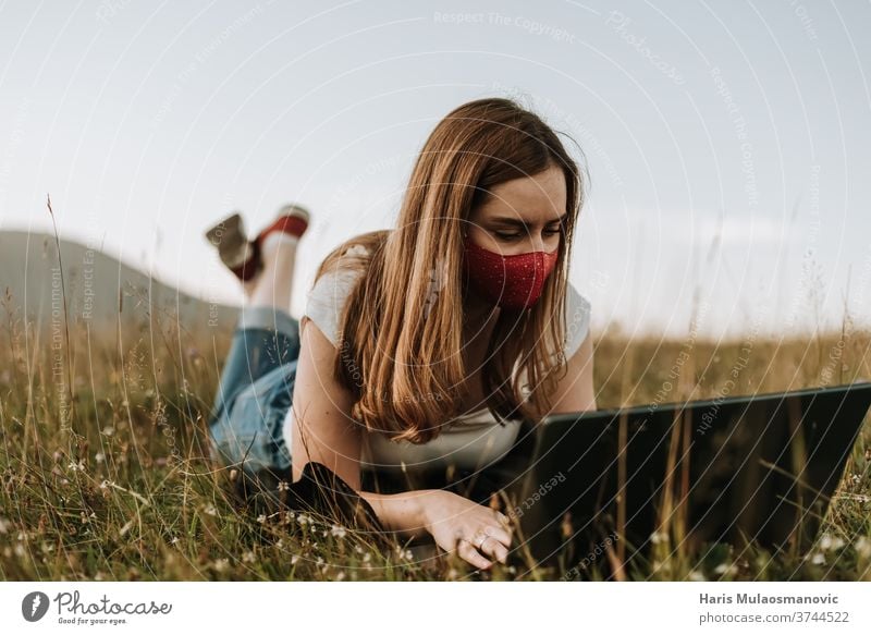 Frau mit Maske, die an einem Laptop im Freien arbeitet Erwachsener attraktiv schön Korona niedlich Tagesablauf Gesichtsmaske Mode Freiberufler Behaarung Glück