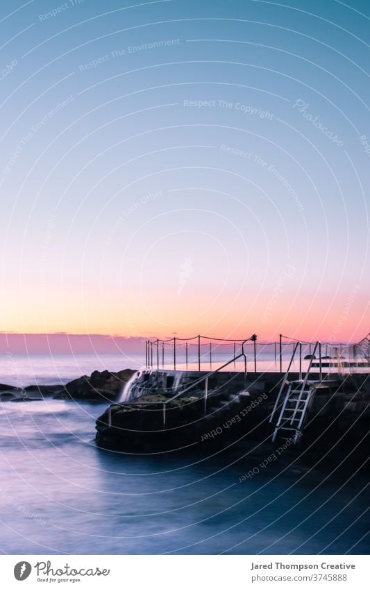 Ein rosaroter Sonnenaufgang im Frühling mit Blick auf die Bronte Baths in Sydney, Australien. bronte Bäder Meer Pool pools nsw newsouthwales Ostküste Strand