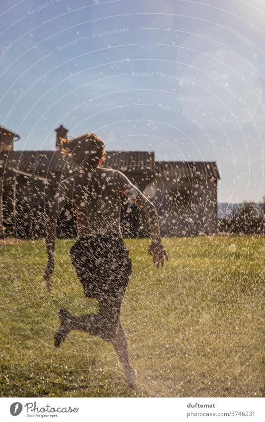 Junger Mann der durch Rasensprenger läuft regen Sommer lustig Spaß laufen Bewässerung Wasser Garten grün Gartenarbeit rennen Frühling teenager Natur