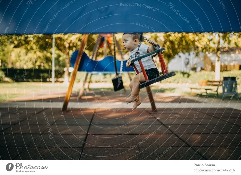 Kind spielt auf der Schaukel Kinderspiel Kindheit 0-12 Monate Spielen Spielplatz pendeln Freizeit & Hobby Kleinkind Tag Mensch Außenaufnahme Freude Farbfoto