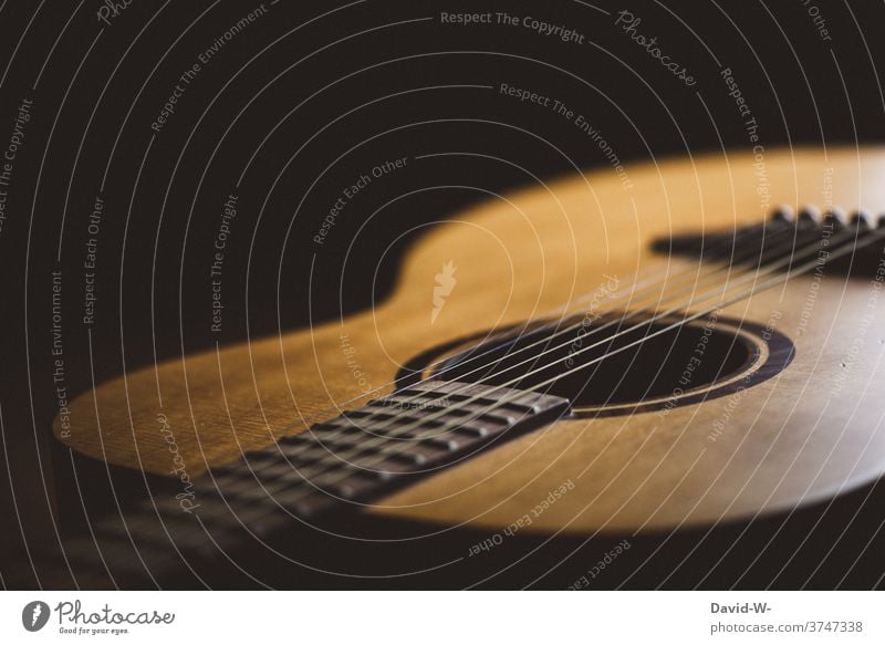 Westerngitarre mit Saiten und Steg Gitarre Musik Instrument saiteninstrument Gitarrensaiten Gitarrensteg dunkel Kontrast Schatten Kultur Licht