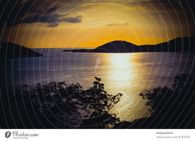 Abenddämmerung, Abend Spektakel auf Thursday Island - Queensland. Die Sonne im wunderschönen Gegenlicht. Hinten zu sehen die Inseln und kleine Wolken. Silbern glänzt das Meer.