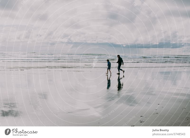 Vater und Sohn laufen als Silhouette am Strand von Oregon Reflexion & Spiegelung Betrachtungen Spiegelung im Wasser Nachdenken & Nachdenken Silhouetten