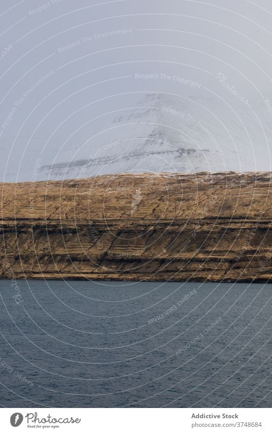 Felsenklippe in Meeresnähe auf den Färöer Inseln Klippe MEER Meereslandschaft Winter Schnee Saison kalt steil Gelände Färöer-Inseln felsig Landschaft