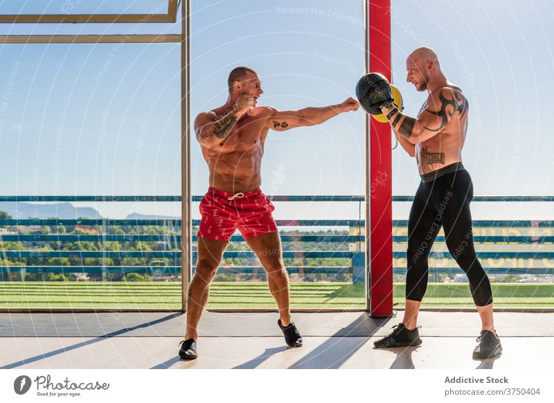 Sportliches Training im Fitnessstudio mit Instruktor Boxsport Bowle Handschuh Mann Trainerin Ausbilderin anstrengen Boxer geräumig Athlet Sportbekleidung