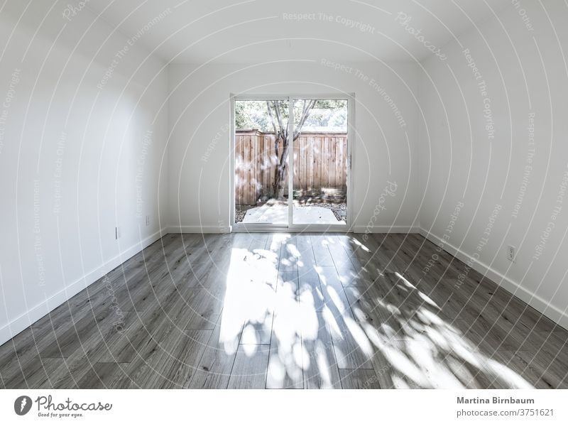 Leeres Schlafzimmer mit großen Glastüren, die in einen Hinterhof führen Raum Kopie wohnbedingt Wohnzimmer Appartement Wand Hintergrund Licht lebend Holz Design